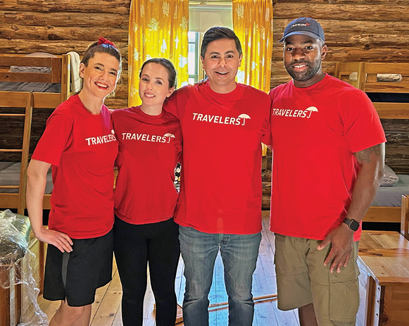 four people in Travelers T-shirts posing in a wooden cabin