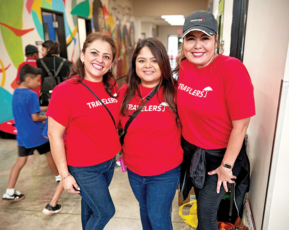 three people in Travelers T-shirts in a school hallway