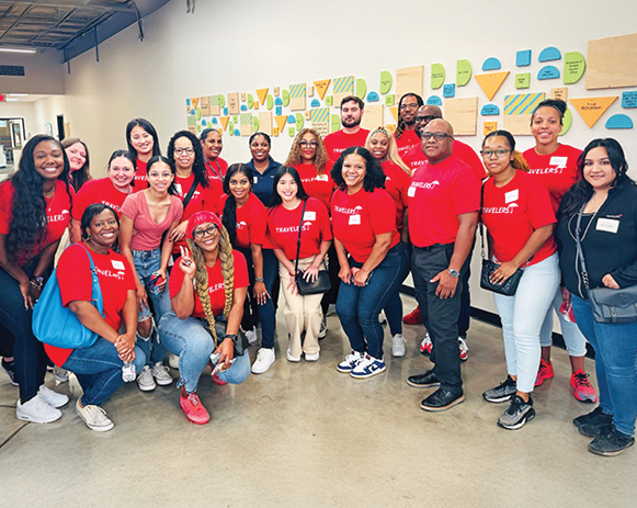 Travelers employees and students posing together in a school hallway