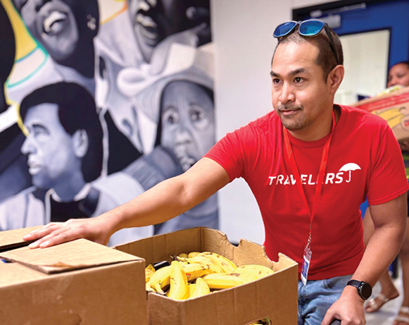 a man in a Travelers T-shirt with a box of bananas