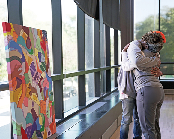 two people hugging near a painting in a hallway