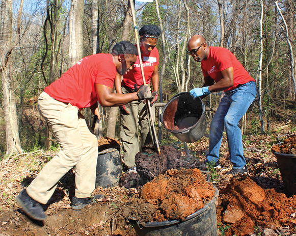 three people in Travelers T-shirts standing, planting a tree