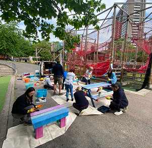 people assembling tables in front of a playscape